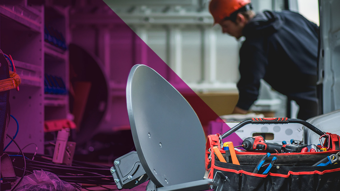 Close-up of a satellite dish and a tool bag with various tools in the foreground. In the background, a person wearing an orange hard hat and black clothing is working inside a van. The image has a purple overlay on the left side.