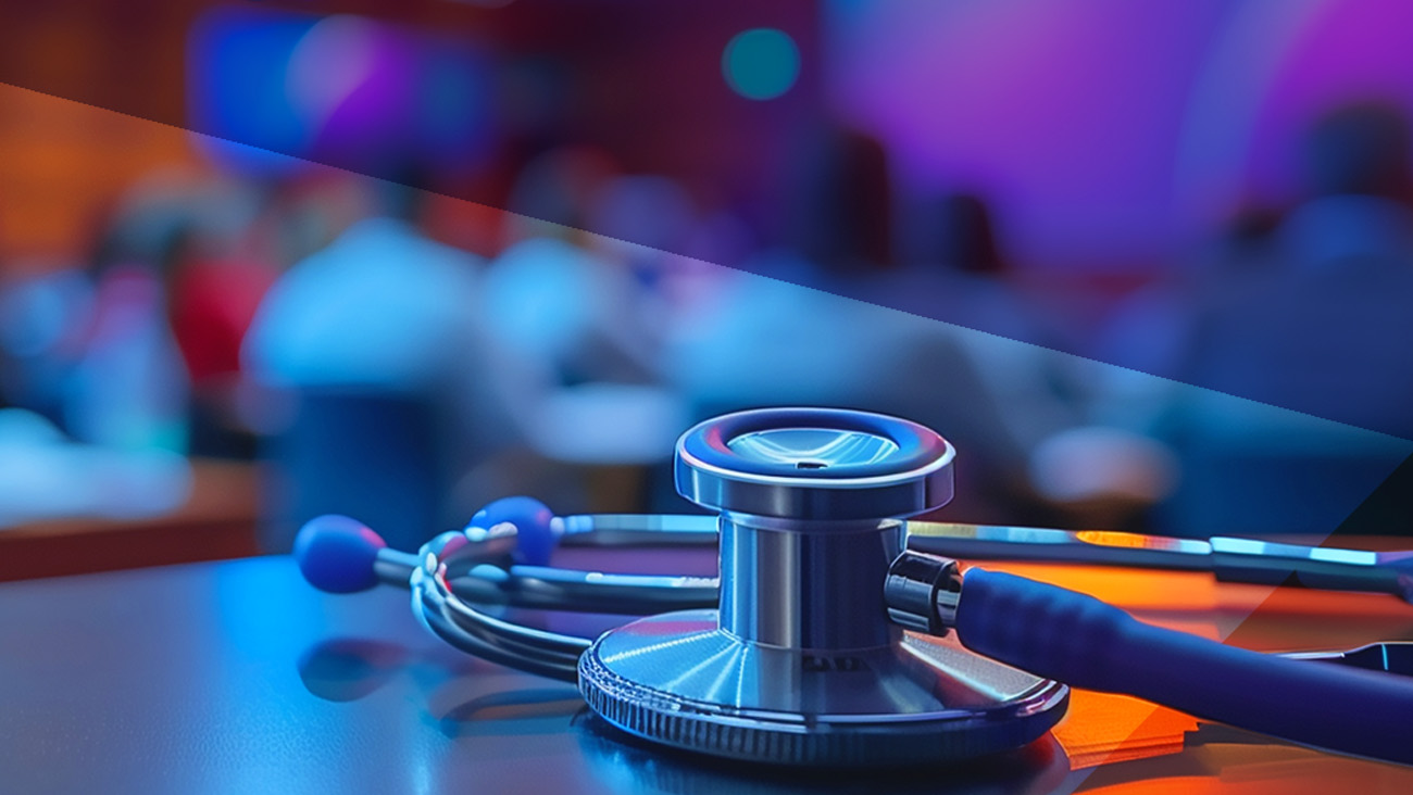 A stethoscope rests on a table in a room with people in the blurred background. The lighting is a mix of blue and purple, giving the scene a modern and professional ambiance.