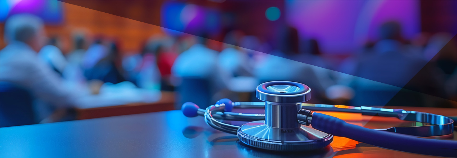 A stethoscope rests on a table in the foreground, with a blurred background featuring an audience of people seated in a conference room. The lighting is a mix of blue and purple tones, creating a professional and modern atmosphere.