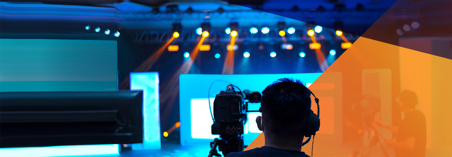 A camera operator films a brightly lit stage with blue and orange lighting effects. Various stage lights create a vibrant backdrop. The scene suggests a live broadcast or concert setting.