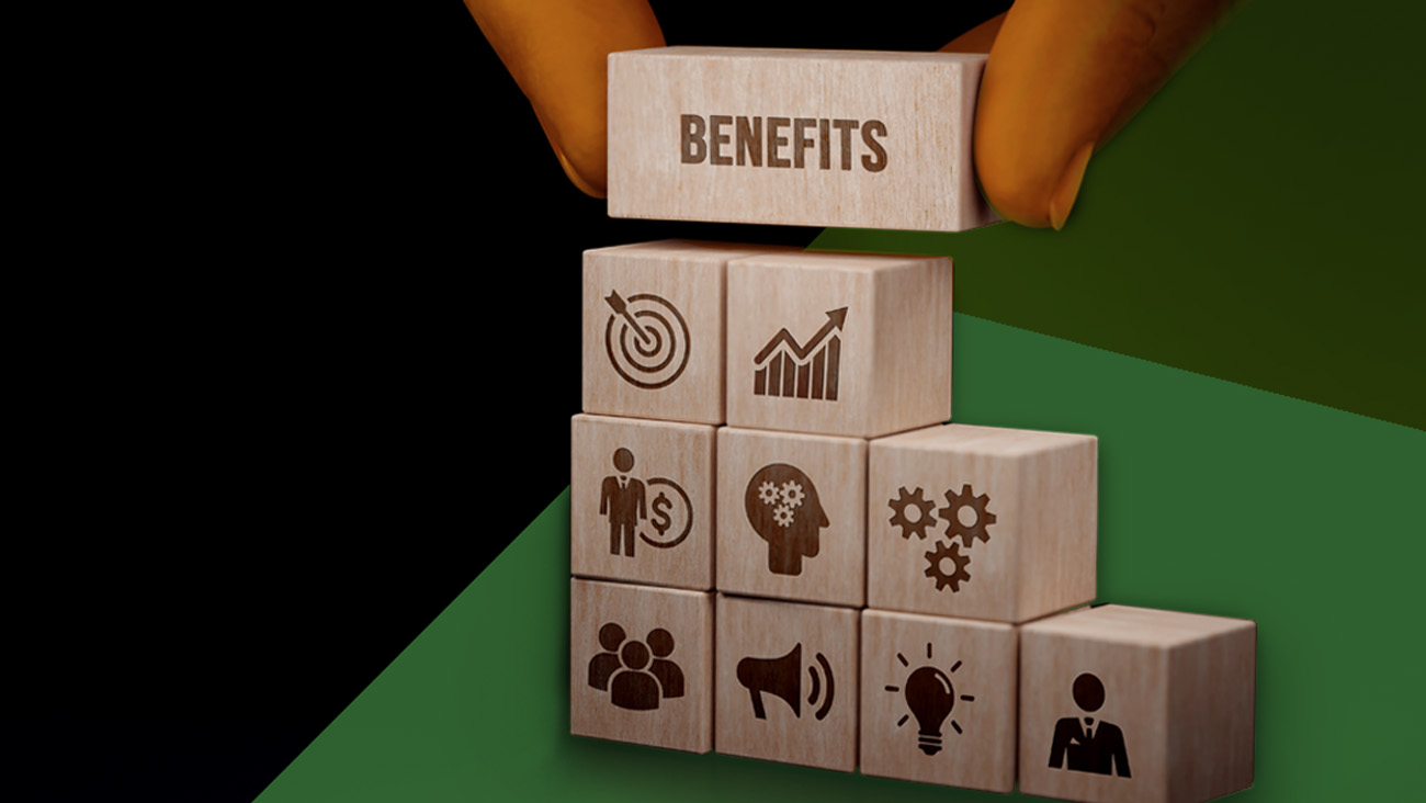 A hand carefully places a wooden block labeled Benefits atop a pyramid of blocks adorned with icons for growth, efficiency, teamwork, and innovation, all framed against a lush green and deep black background.