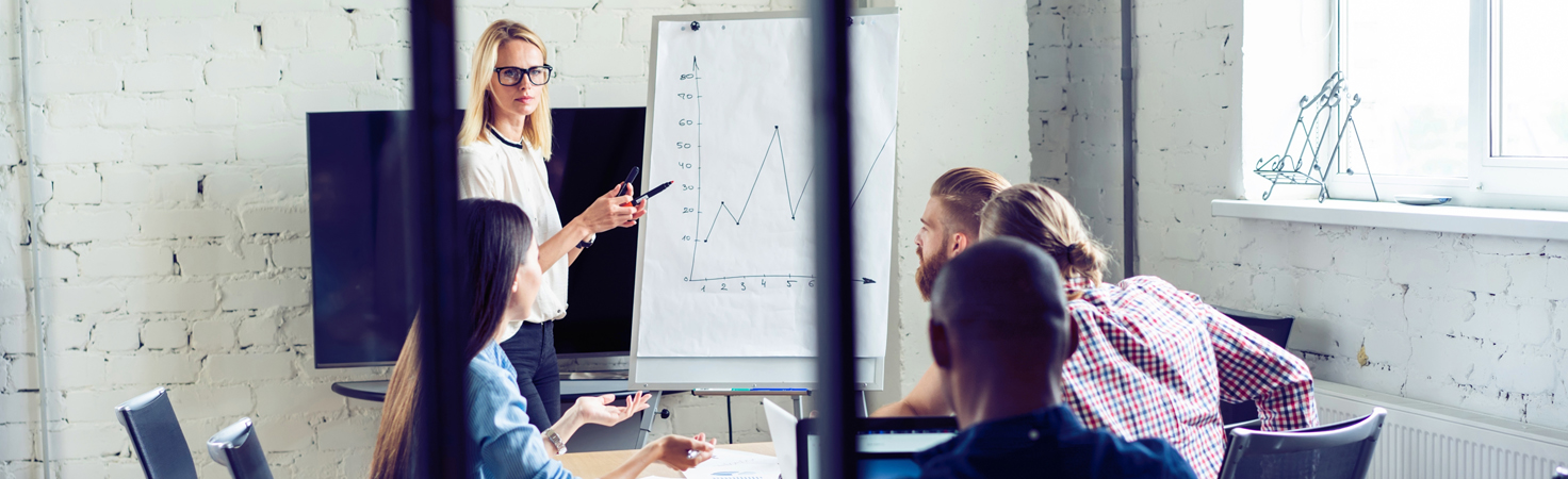 team of salespeople in a meeting looking at a white board