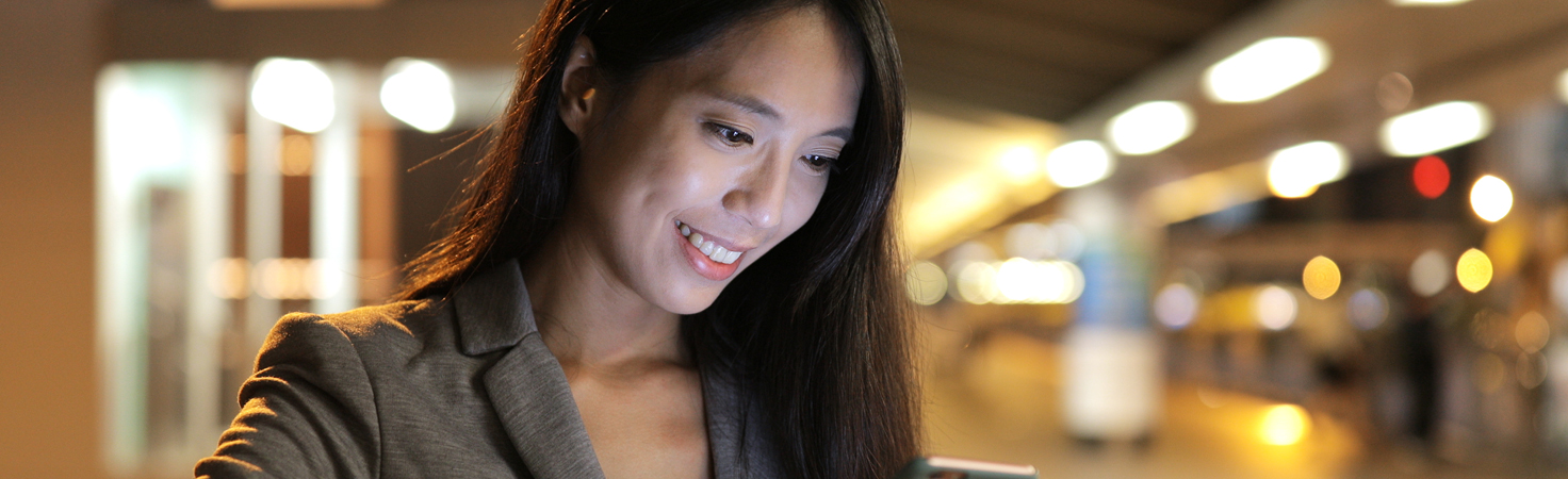 Business woman looking on mobile phone at night